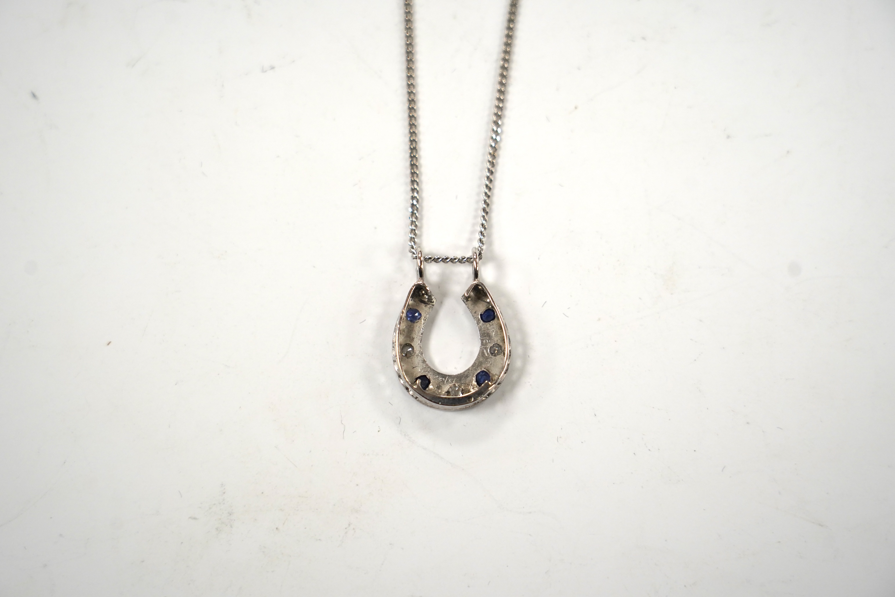 A modern 18ct white gold, sapphire and diamond set horseshoe pendant on chain, overall 44cm, gross weight 5.5 grams. Condition - fair